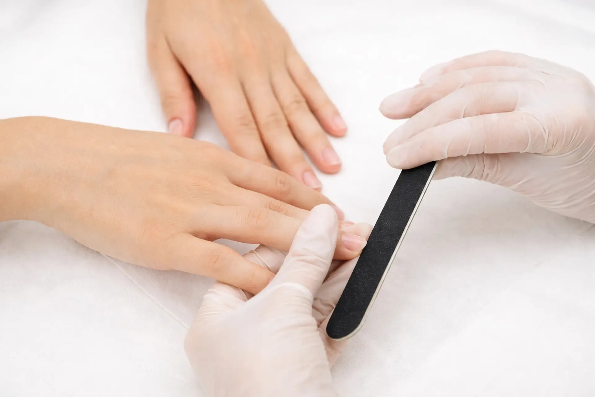 Nail technician shaping nails during a professional manicure at Aura Day Spa in Thunder Bay.